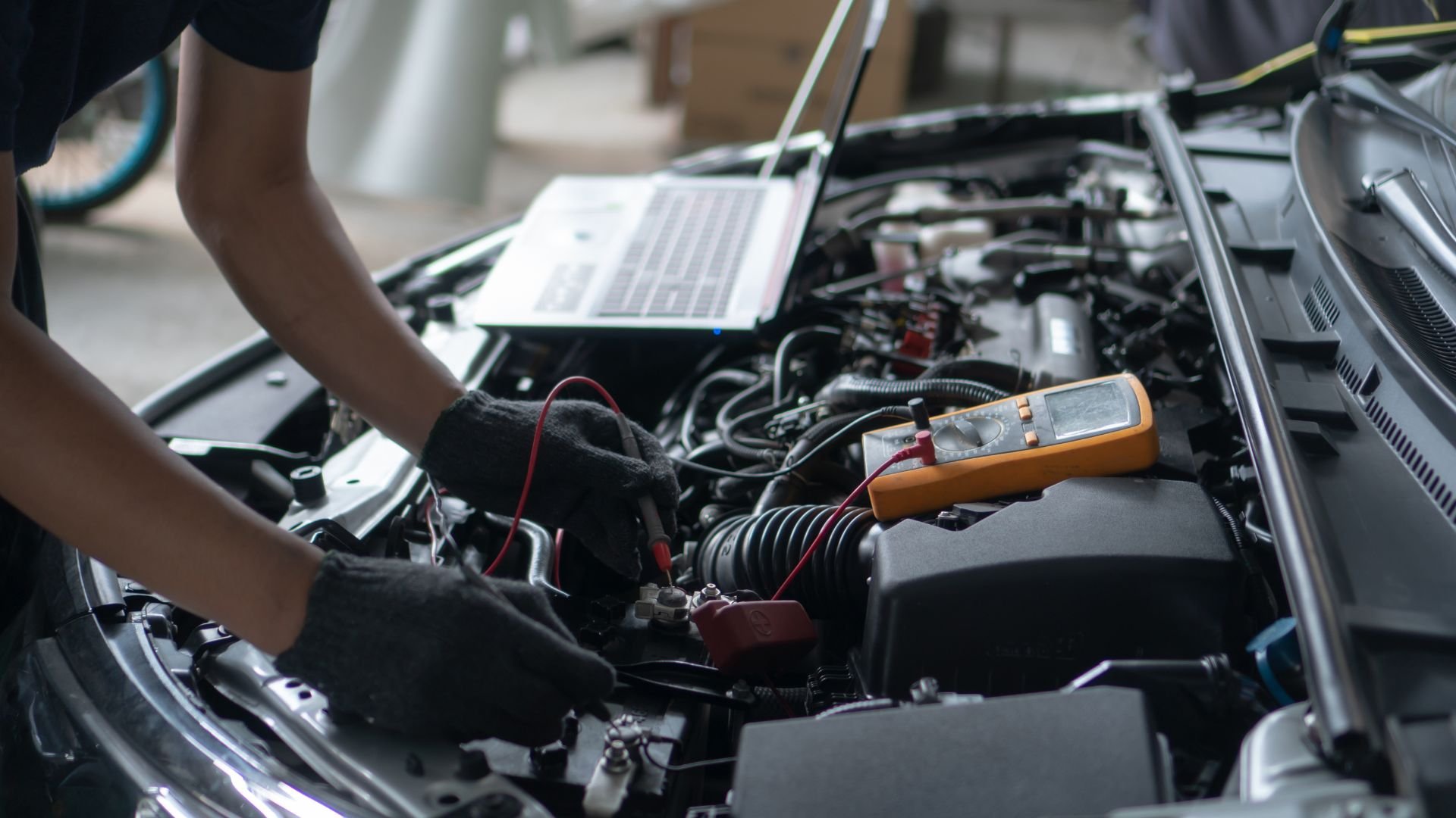 Mechanic using multimeter to diagnose car engine electrical issues