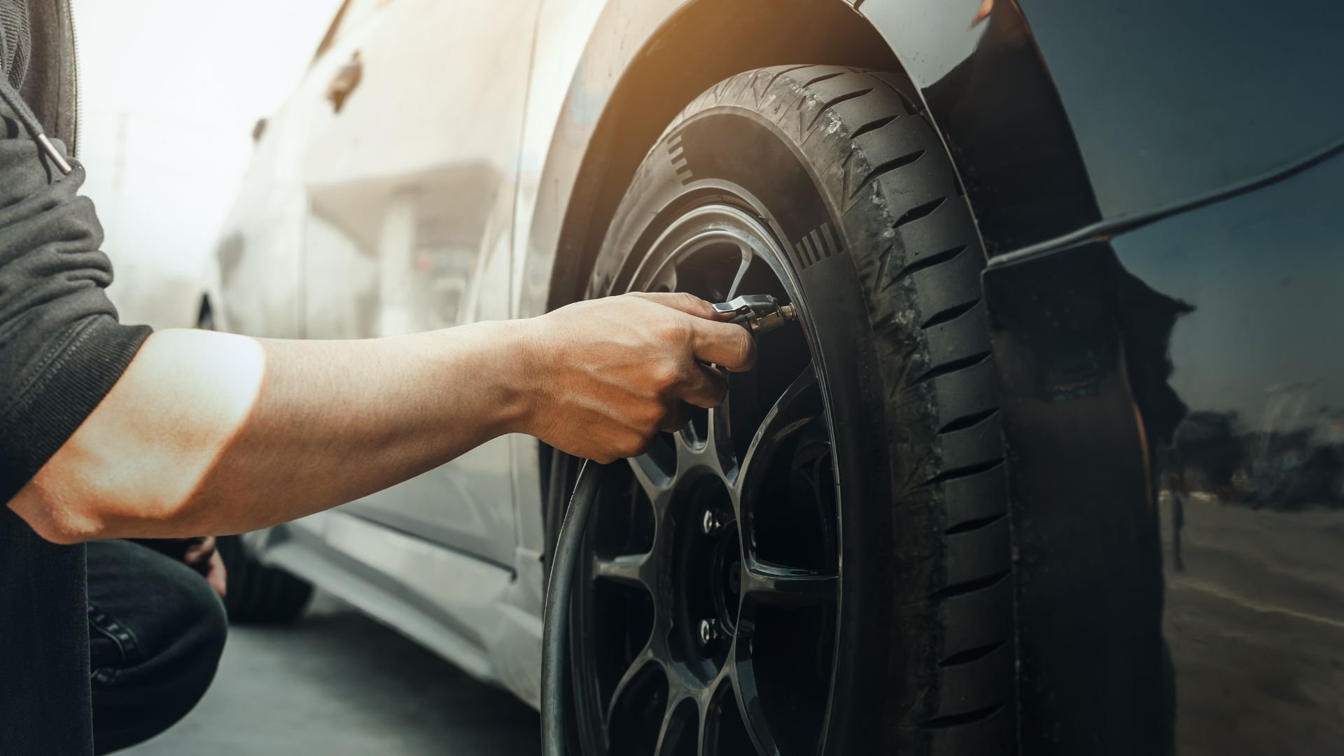 Hand inflating car tire with air pressure gauge at service station