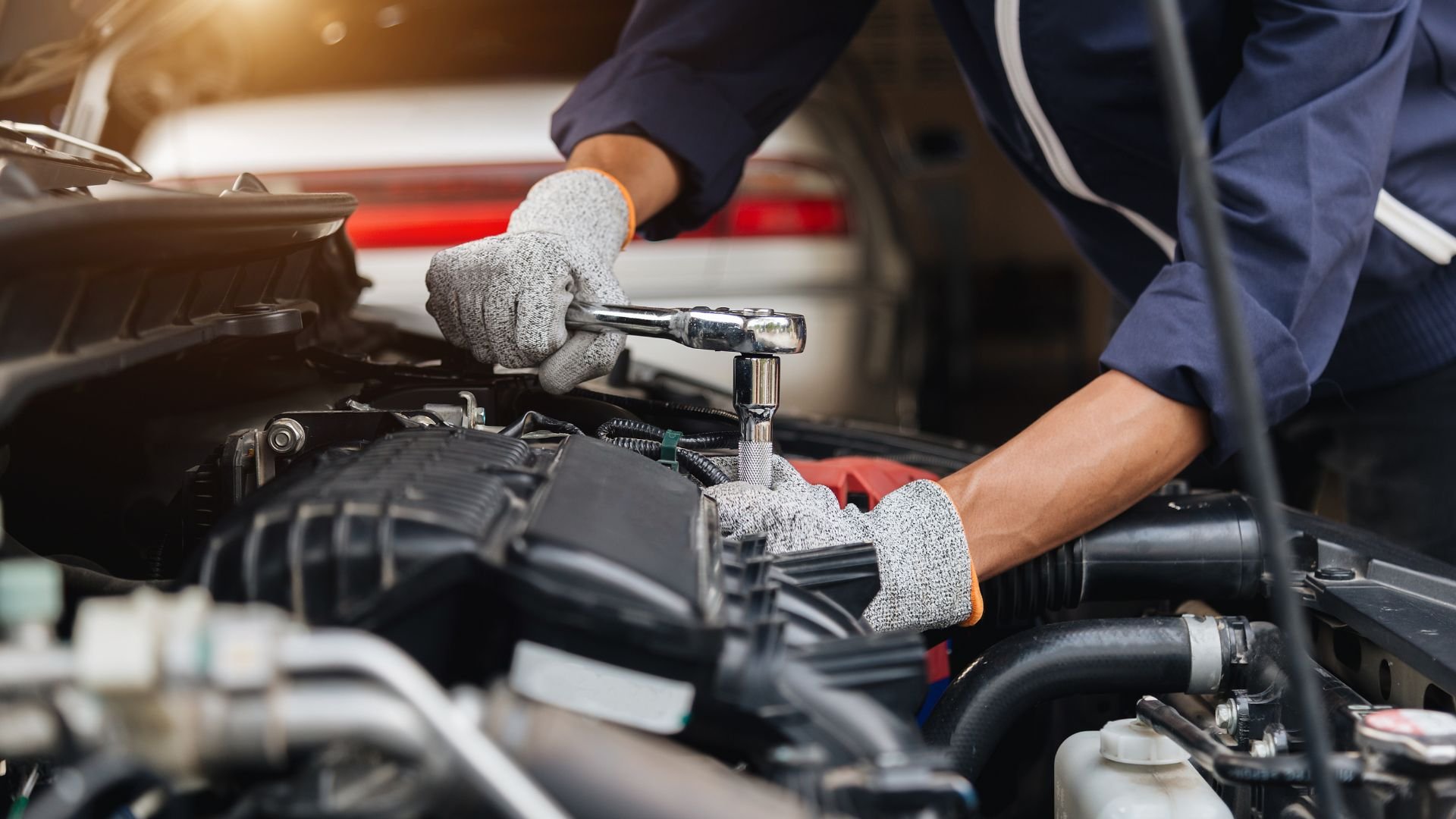 Mechanic using wrench to repair car engine in automotive workshop