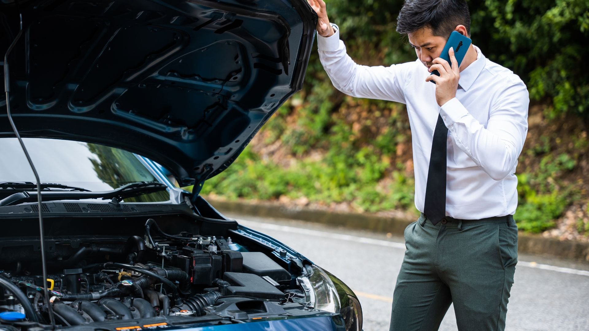 Professional in white shirt calling for help with broken down car